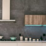 Modern kitchen range hood above a stove with cooking pots