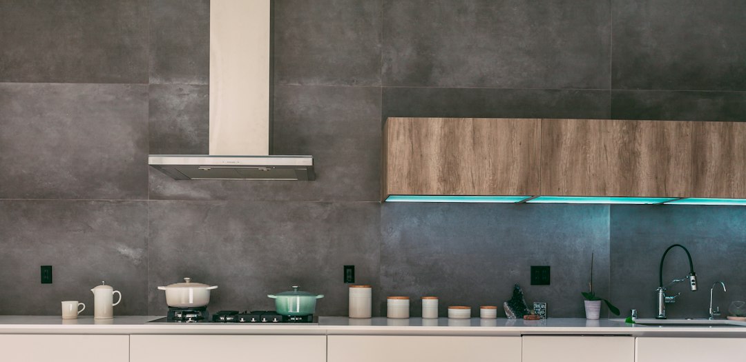 Modern kitchen range hood above a stove with cooking pots